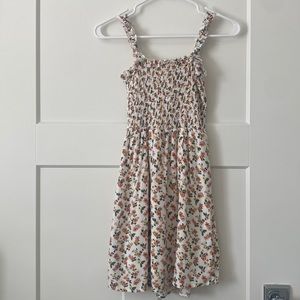 white dress with orange, pink, yellow flowers and green leaves.